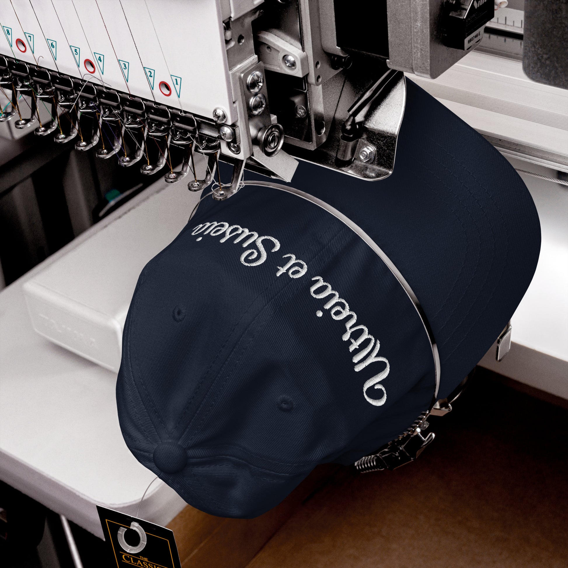 Stickmaschine, wie sie eine navy farbene ltreia et Suseia Cap bestickt